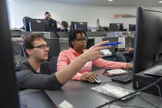 professor points to a student's computer in a lab.