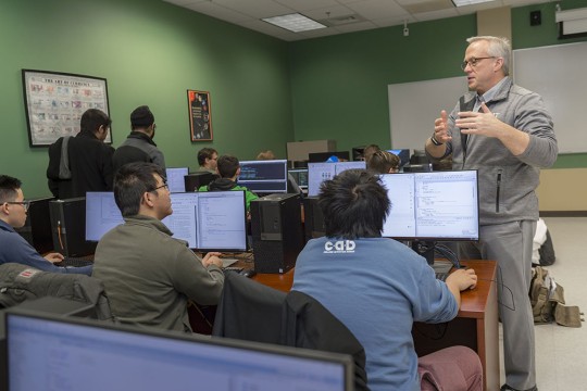 Professor teaching students who are sitting at computers.