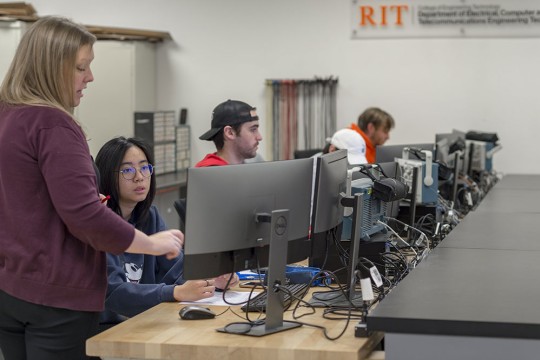 Professor teaching students who are sitting at computers.