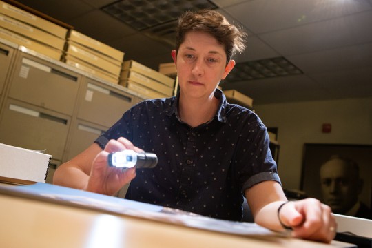 An I P I employee shines a light on a specimen to examine it.