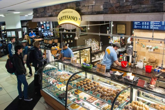Customers in line next to clear storage racks showing off baked goods.