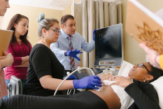 A group of people performing a sonogram on a patient