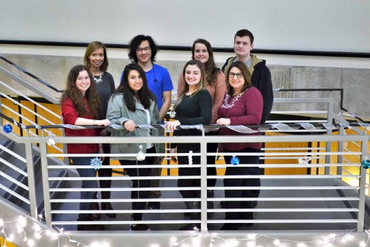Eight people standing on a staircase landing posing for a photo
