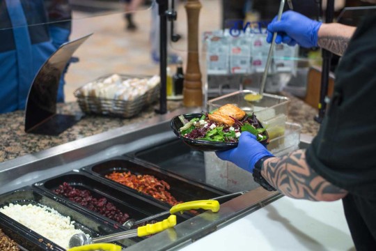 Over the shoulder shot serving a salad to a customer