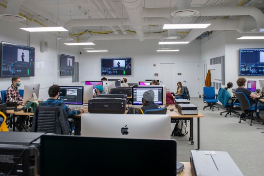 a computer lab with Mac computers with students working on them.