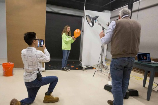 3 people capturing a balloon pop with video equipment