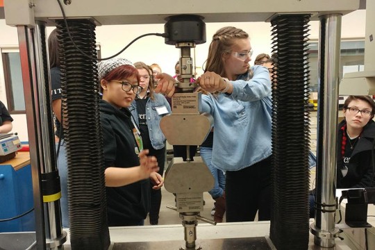A group of students work with a large piece of lab equipment.