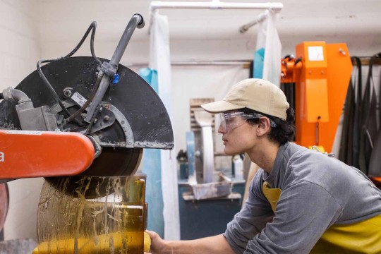 Student cutting a block of glass with a large wet saw