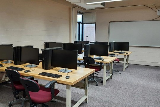 A computer lab with rows of tables with computers and chairs.