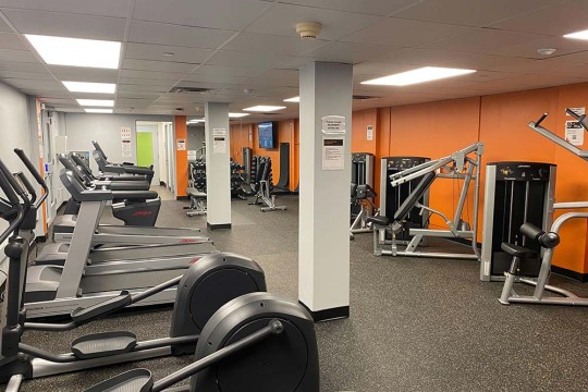 a gym space with cardio equipment, weight lifting equipment, and free weights.