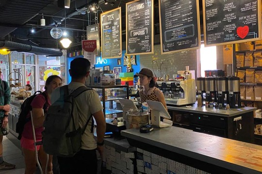 Students ordering at the Java's counter with menu behind cashier.
