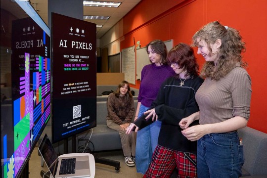 Students look at large touchscreen displays.