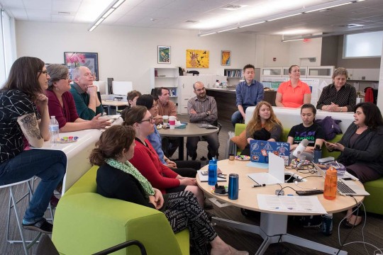 A large group of people sitting on chairs and a couch in a circle during a discussion