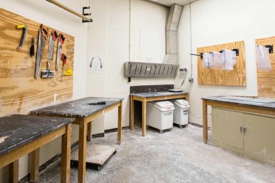 Workroom with workbenches with hand saws hanging from the wall