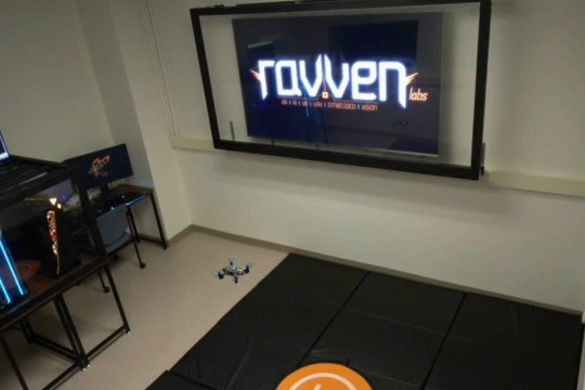 a lab with a large screen and a small drone flying.