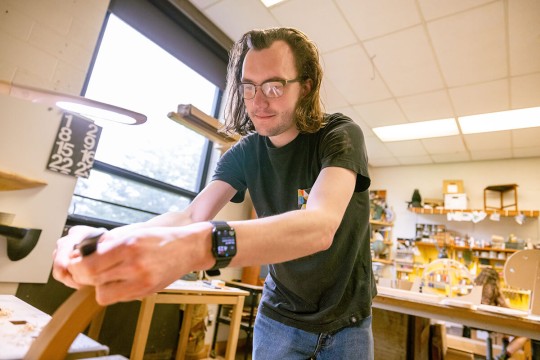 An R I T student works with hand tools in the furniture design studio.