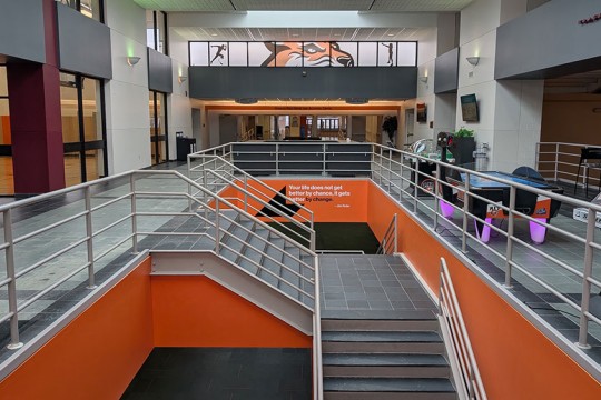 lobby area with an air hockey table and stairways that lead to a lower level.