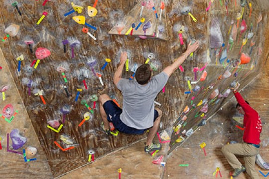 Two people hanging off of an indoor rock wall