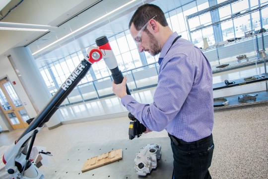 Man with goggles doing a laser scan of a manufacturing part.