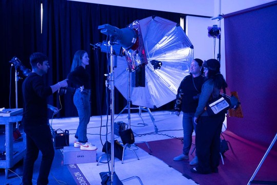 students working with photo equipment in a room in blue lighting.