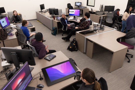 students sitting at several workstations with computers and drawing pads called Cintiqs.
