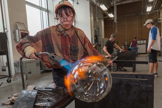 A student lights a torch to a glass object.