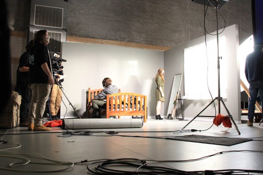a scene in a sound studio with student actors sitting on a bed and looking at a mirror.