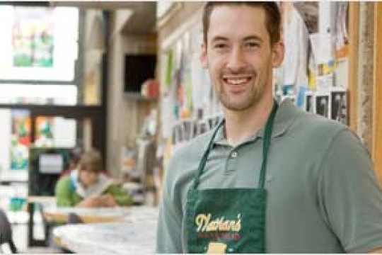 Man wearing a green shirt and a Nathan's bakery apron