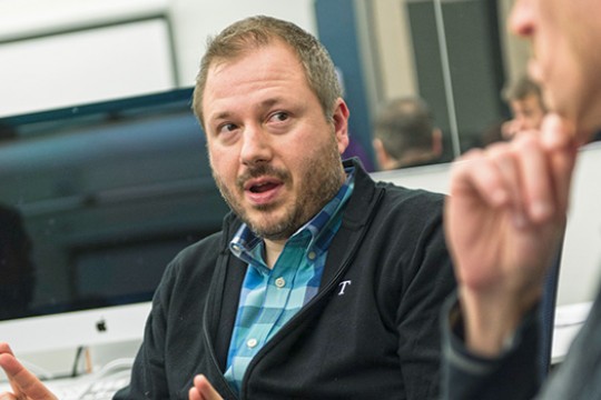 A headshot of Matt Huenerfauth talking to a colleague.