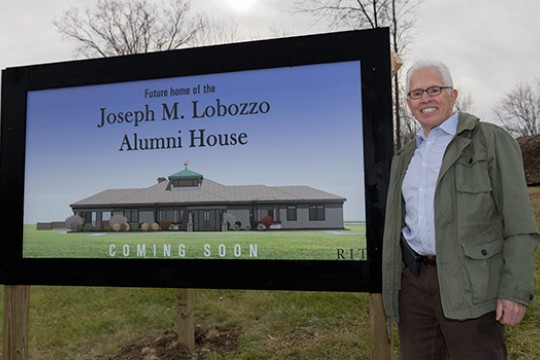 man standing next to a sign that says, future home of the Joseph M. Lobozzo Alumni House.