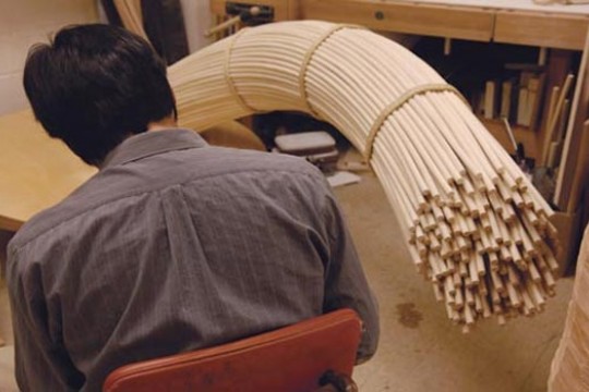 artist holding bundle of dowels.