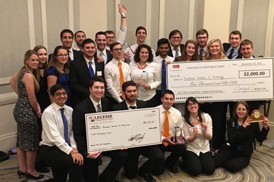 The teams who attended the Associated Schools of Construction annual design competition pose for a photo with their large checks and other awards.