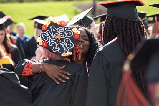 two graduates hugging. graduate cap saying "class of 2018".
