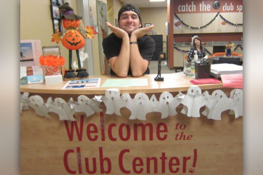 Person posing at the welcome to the Club Center! desk