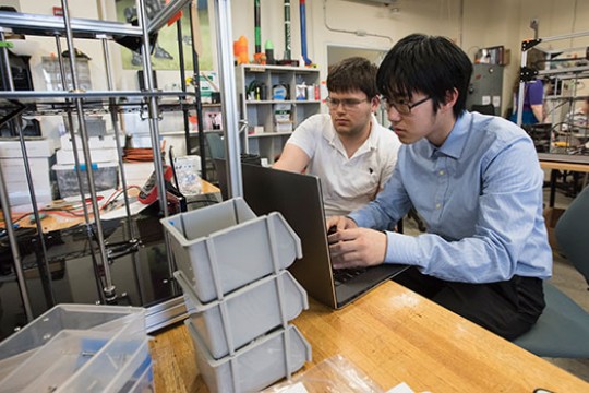 two students working on a laptop in maker space.