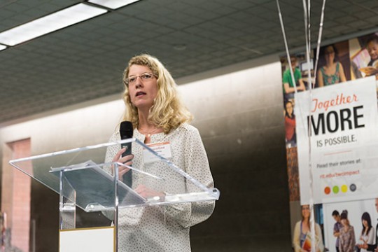 Blonde woman speaking at podium.