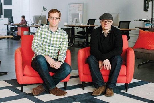 Two people posing for camera in office