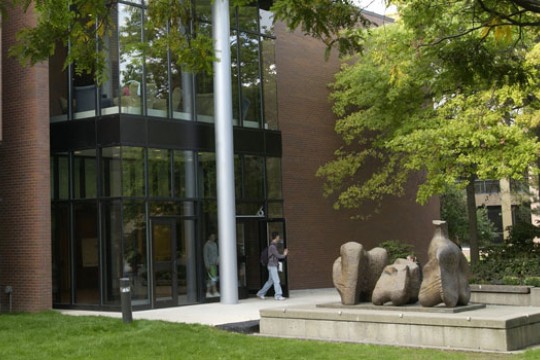 Students walk out of building near statue