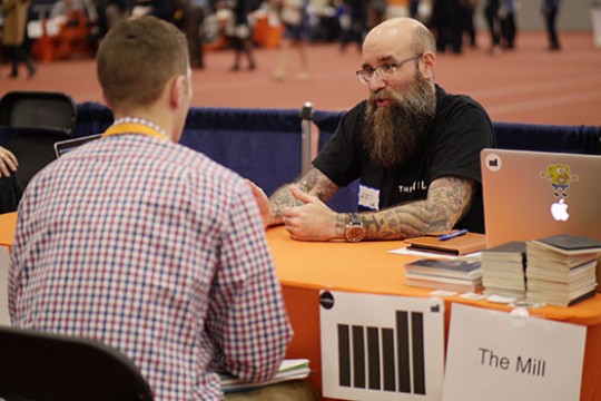 Image of two people sitting across from each other at a table in the field house.