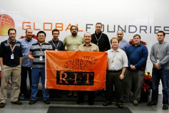 People posing with RIT flag infront of Global Foundries sign