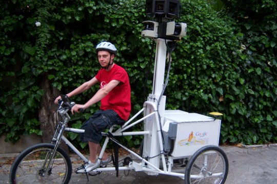 Person riding tricycle with machine on the back