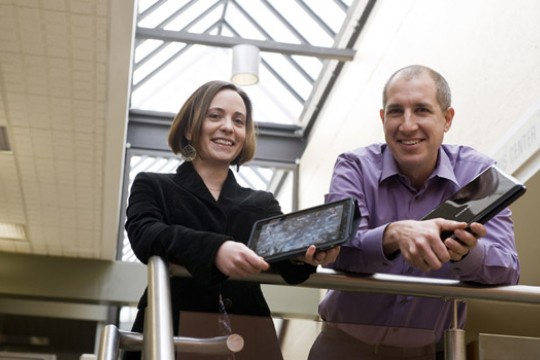 People posing with tablets side by side