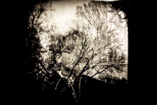 a photograph mixing in the image of a person and tree branches.