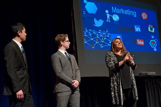Three people standing on stage presenting innovative ideas of deaf and hard-of-hearing students.