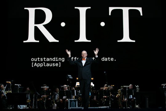 RIT President, Dr. Munson, standing on a stage in front of a band.