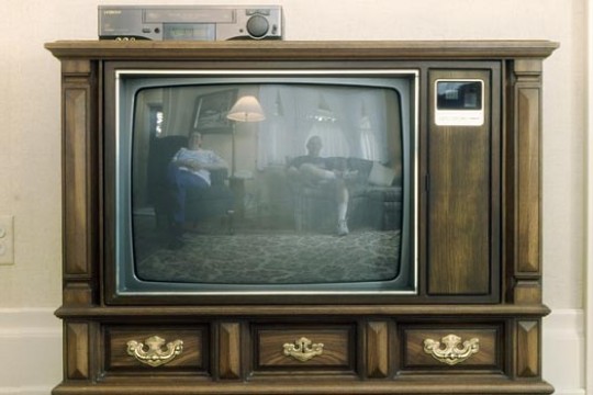 Old fashion box television with two people on screen