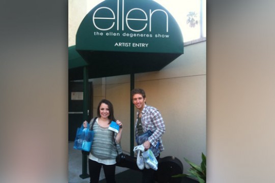 Two people posing in front of sign for the Ellen DeGeneres show.