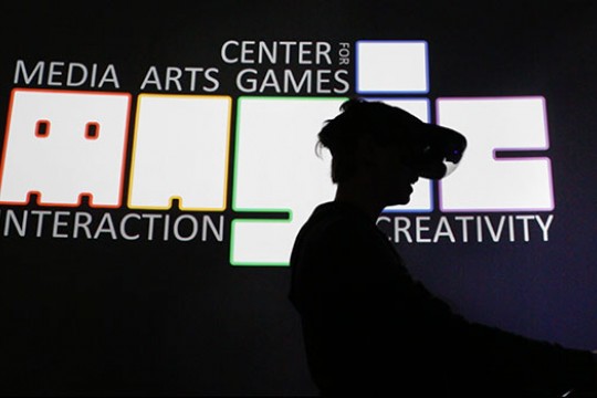 Student with VR headset, in front of the MAGIC logo.