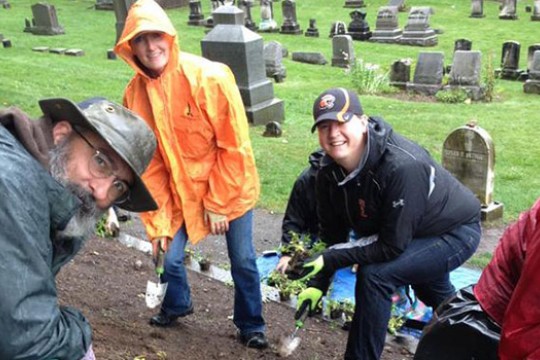 People planting flowers in graveyard