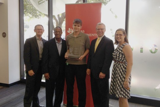 People posing in front of "Texas Instruments" poster